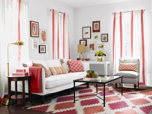 Phòng khách sáng sủa với sofa trắng, ghế đơn, thảm họa tiết hồng đỏ và bàn trà kính