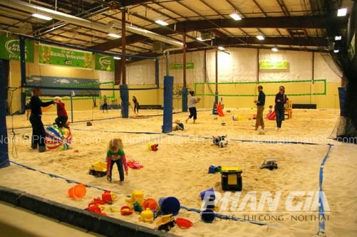 Sân cát trong nhà với lưới bóng chuyền và trẻ em chơi đồ chơi trên cát