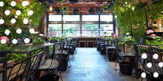Thiết Kế Không Gian Quán Cafe Đặc Biệt 5 Không gian quán cafe nhiều cây xanh, đèn tròn treo và bàn ghế sắt